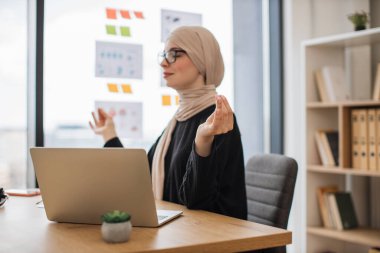 Yan görüntüde, Gyan Mudra 'da koltukta dinlenirken kollarını tutan gözleri kapalı Arap bir kadın var. Önemli pazarlıklardan önce tesettür geliştirmede etkili bir profesyoneldir..