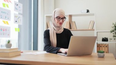 İş yerinde taşınabilir bilgisayar kullanarak etkileşimli grup toplantısına ev sahipliği yapan tesettürlü güzel bir Arap kadın. Verimli baş yönetici bölge ofislerinden pazarlama ekipleriyle konuları tartışıyor..