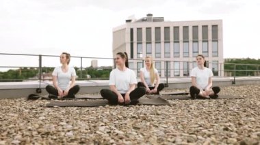 Yoga pratisyenlerinin açık terasta kalırken mudra hareketiyle nilüfer pozisyonunda durdukları düşük açılı görüş. Aktif giyinen rahat kadınlar açık hava dersleri sırasında derin meditasyona hazırlanıyor..