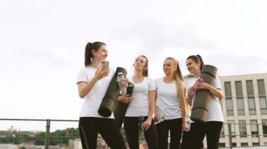 Bir grup beyaz kadın ellerinde paspas ve su şişeleriyle akıllı telefondan kendi fotoğraflarını çekiyor. Neşeli yoga aşıkları kamerada arkadaşlarıyla dışarıda yaptıkları egzersizlerin anılarını yakalıyorlar..