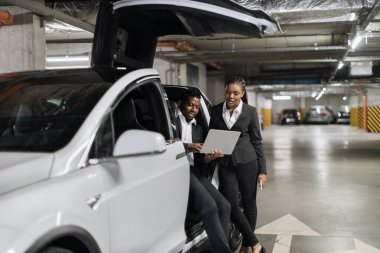 Yeraltındaki garajda EV 'nin yanında kalırken bilgisayarla resmi tartışmalara katılan Afrikalı iş arkadaşlarına odaklan. Ortak sorunları çözmek için park zamanını verimli bir profesyonel olarak kullanıyor..