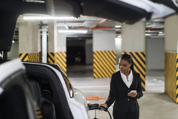Fokus Pada Wanita Menarik Dengan Ponsel Berdiri Dekat Mobil Listrik — Stok Foto