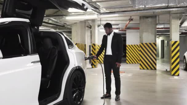 Стильний Афроамериканський Чоловік Заповнює Електромобіль Підвальному Гаражі Орієнтований Бізнесмен Офіційному — стокове відео