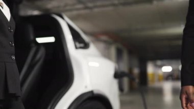 Otopark arka planında yukarı aşağı hareket eden erkek ve kadın avuçlarının yakın görüntüsü. Tecrübeli iş arkadaşları elektrikli otomatiğe karşı el sıkışarak kooperatif davranışı teşvik ediyorlar.