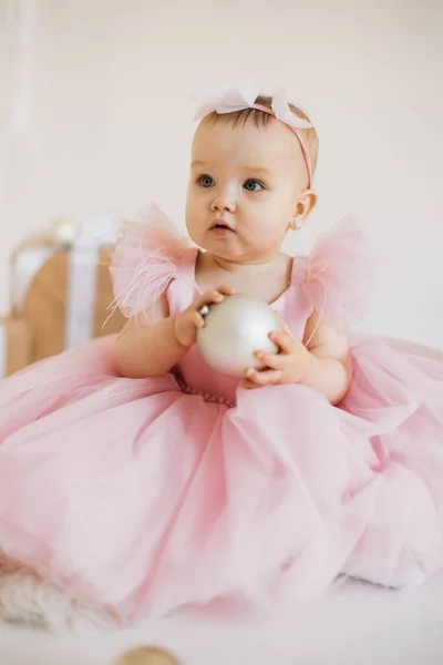 身穿节日服装的美丽的小公主手拿白球坐在装饰过的演播室里 迷人漂亮的幼儿 头戴可爱的头巾 把目光投向一边 享受生日派对 — 图库照片