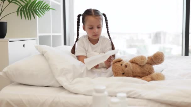 코카서스 소녀는 그녀의 장난감과 침대에 냅킨에 집에서 머물면서 감기와 바이러스를 — 비디오
