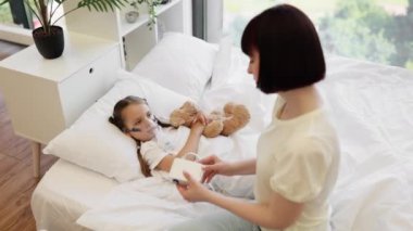 Beyaz bir kızın portresi oyuncak ayıyla yatakta uzanıyor ve nebulizmanın dumanını soluyor şefkatli bir annenin yardımıyla. Beyaz kadın, hasta kızına evde annelik yaparak bakıyor..