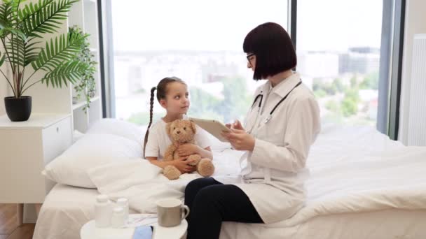 Doświadczona Pediatra Pisząca Tablecie Cyfrowym Szczegółowe Informacje Małym Chorym Pacjencie — Wideo stockowe