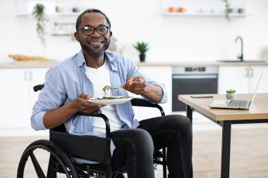 Salata, yemek odasında özürlü bir Afrikalı tarafından dizüstü bilgisayarın yanına yerleştirilmiş. Mesut işletme müdürü gün ortasında evden işe giderken sağlıklı yiyeceklerin tadını çıkarıyor..