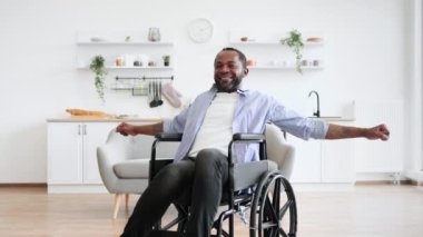 Memnuniyetle Afrikalı erkek antrenman yapıyor ve güneşli bir günde evde elini kaldırıyor. Gülümseyen olgun insan sakatlık egzersizi yaparken dayanıklılığını artırıyor..