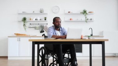 Afrikalı tekerlekli sandalye kullanıcısı uzak işyerinde kalarak başarıyı kutluyor. Evden tam zamanlı iş yaparken neşeli profesyonel iş projesi.