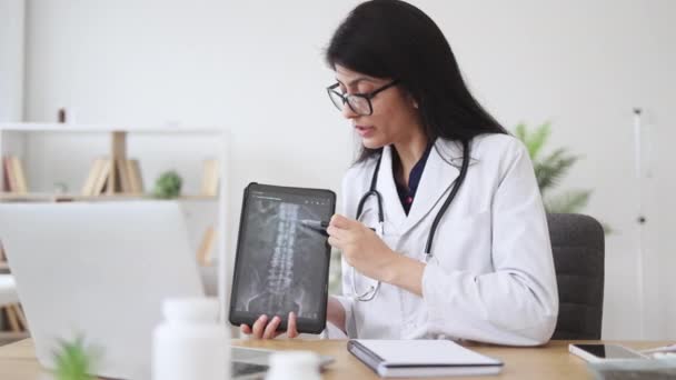 Médica Madura Casaco Branco Sentada Mesa Apontando Para Coluna Ray — Vídeo de Stock