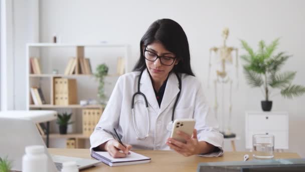 Vážná Lékařka Lékařských Šatech Která Používá Moderní Smartphone Dělá Poznámky — Stock video