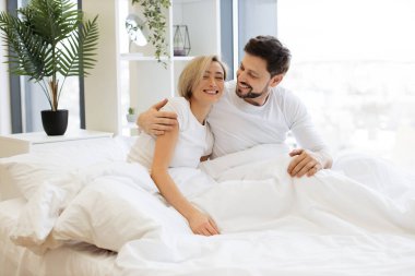 Parlak yatak odasında yatarken, gece uykusundan sonra kucaklaşan beyaz tenli çiftlere bayılıyorlar. Rahat aile babası ve kadın modern dairede güneşli bir güne başlıyorlar..