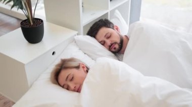 Beyaz tişörtlü çekici bir erkek arkasında güzel genç bir bayanla birlikte kestiriyor. Kafkasyalı mutlu çift sabah rüyalarında rahat bir hayat sürüyor..