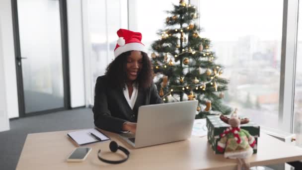 Afrikanische Geschäftsfrau Mit Weihnachtsmütze Sitzt Büro Der Nähe Des Weihnachtsbaums — Stockvideo