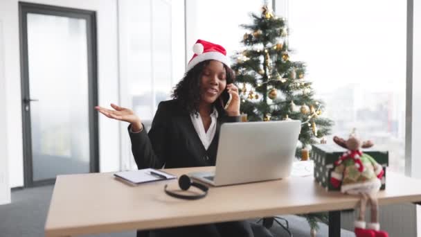 Noel Ağacının Arka Planında Taşınabilir Bilgisayar Kullanırken Akıllı Telefondan Konuşan — Stok video