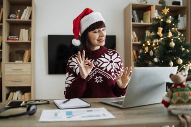 Noel Baba şapkalı mutlu bir kadın müşteriyle telefonda konuşurken Noel 'de evde kalıp tabela gösteriyor..