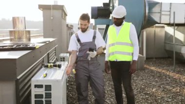 Beyaz sakallı inşaat ayakta duruyor ve klima için ölçüm cihazı kullanırken afro meslektaşı dışarıda pozitif sonuç doğruluyor. Onarım ve aygıt arızası kavramı.