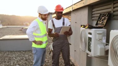 Çalışkan erkek işçiler dışarıda kişisel tabletlerdeki online belgeleri imzalarken el sıkışıyorlar. Sorumlu havalandırma uzmanları iş sırasında temiz hava konusunda anlaşma yapıyorlar..