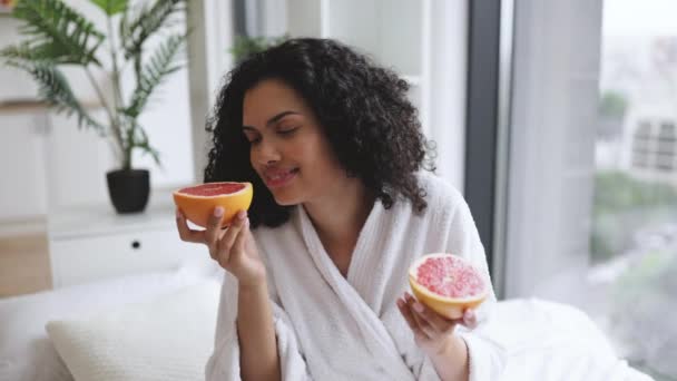 健康的女性沐浴后 享受新鲜柑橘类水果的芬芳 同时在安静的卧室里放松 迷人的成年人使用富含维生素C柚子的高端美感生活 — 图库视频影像