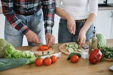 Beyaz, yaşlı, evli bir adamın elleri, sağlıklı bir salata hazırlıyor, yeşil sebze ve domatesleri ince ince dilimliyor ve geniş bir mutfak arka planına bıçak dayanıyor..