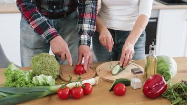 Beyaz, yaşlı, evli bir adamın elleri, sağlıklı bir salata hazırlıyor, yeşil sebze ve domatesleri ince ince dilimliyor ve geniş bir mutfak arka planına bıçak dayanıyor..
