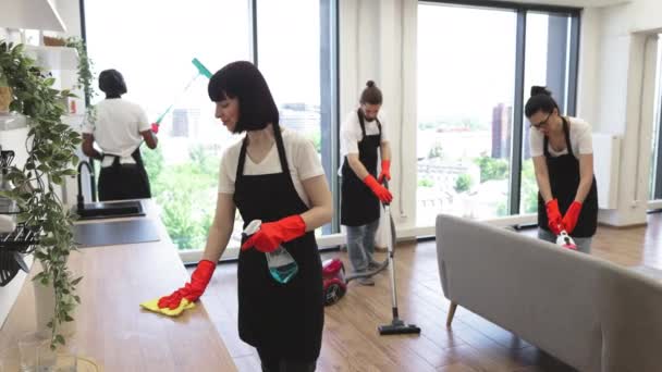 一个白人年轻女人在厨房里擦桌子的画像 女管家队身穿黑色制服围裙 并在家中派驻红胶手套清洁服务队 — 图库视频影像