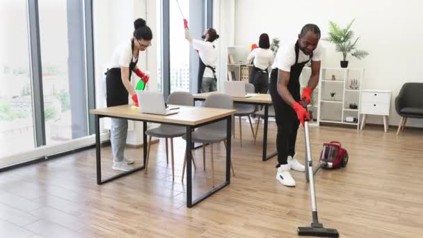 年轻的多文化清洁工团队清理地板 擦桌子和小玩意 洗窗户在宽敞 现代的办公室 专业清洁公司 — 图库视频影像