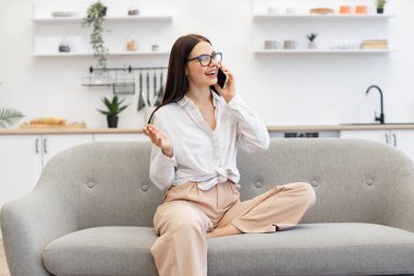 Kafkasyalı esmer, modern aletler kullanıyor ve hafta sonu iş görüşmelerinde ara veriyor. Güzel bir kadın evdeki kanepede dinleniyor ve modern akıllı telefonu ailesiyle konuşmak için kullanıyor..