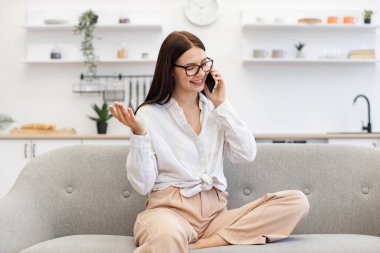 Kafkasyalı esmer, modern aletler kullanıyor ve hafta sonu iş görüşmelerinde ara veriyor. Güzel bir kadın evdeki kanepede dinleniyor ve modern akıllı telefonu ailesiyle konuşmak için kullanıyor..