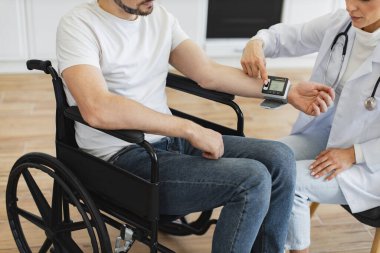 Engelli kadın doktor ve hasta ekinleri mutfakta teşhis ve sağlık kontrolünden bahsediyorlar. Elektronik ekranı olan özenli bir adam kadın doktoru dikkatle dinliyor..