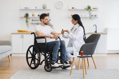 Vücut ısısı ölçümü. Kızılötesi lazer temassız termometre. Kadın doktor termometreyi evde sakat bir hastayla erkeğin vücut ısısını ölçmeye hazır tutuyor..