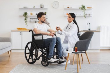 Vücut ısısı ölçümü. Kızılötesi lazer temassız termometre. Kadın doktor termometreyi evde sakat bir hastayla erkeğin vücut ısısını ölçmeye hazır tutuyor..