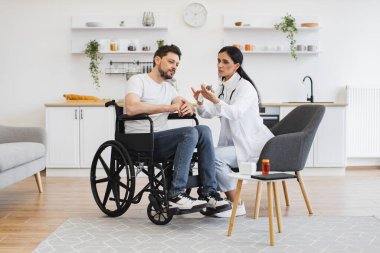 Kadın doktor termometreyi evde sakat bir hastayla erkeğinin vücut ısısını ölçmek için hazır tutuyor. Vücut ısısı ölçümü. Kızılötesi lazer temassız termometre.
