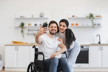 Tekerlekli sandalye kullanıcısı ve karısı boş zamanların tadını çıkarırken telefon kamerasıyla günlük kıyafetlerini giyiyorlar. Engelli bir ailenin internet üzerinden telefon görüşmesi yapması ve akrabalarıyla konuşması.