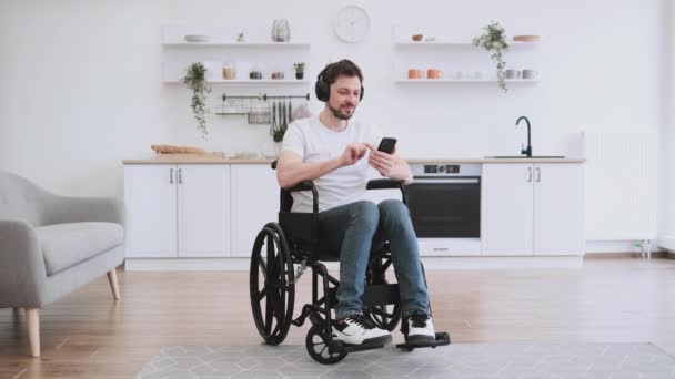 Радостный Мужчина Белой Футболке Поднимает Руку Глядя Смартфон Сидящий Инвалидной — стоковое видео