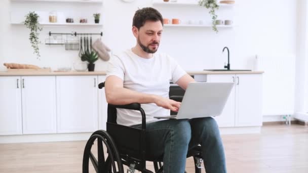 Radosny Biały Mężczyzna Wózku Inwalidzkim Trzymający Laptopa Kolanach Podczas Pobytu — Wideo stockowe