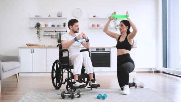 Vrouw Sportkleding Helpen Volwassen Man Rolstoel Tillen Armen Met Stretching — Stockvideo