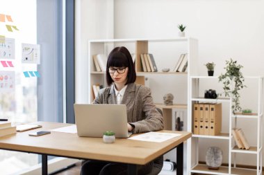 Resmi olarak kendine güvenen genç çalışan modern ofiste masa başında şifreli dizüstü bilgisayarın kilidini açıyor. Yaratıcı iş yerinde arama motoru kullanarak ticari markaları araştıran beyaz kadın işçi..