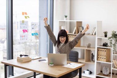 Modern ofiste mutluluk çığlıkları atarken el ele tutuşan gözlüklü duygusal genç bayan. Heyecanlı Kafkas uzmanı iş yerinde büyük bir coşkuyla ihaleyi kazandı..