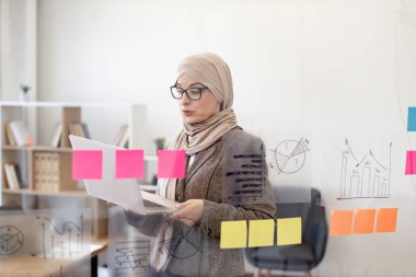 Resmi giyinen kendine güvenen Müslüman kadın şirket yönetim kurulundayken dizüstü bilgisayarla iş sorunları çözüyordu. Modern teknoloji ve meşgul insanlar kavramı.