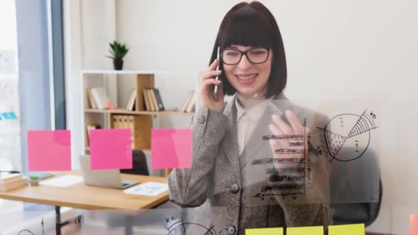 女行政主管准备在工作中发言 在办公室开会前 戴眼镜的白人妇女在智能手机上交谈 在玻璃墙上看财务图表 — 图库视频影像