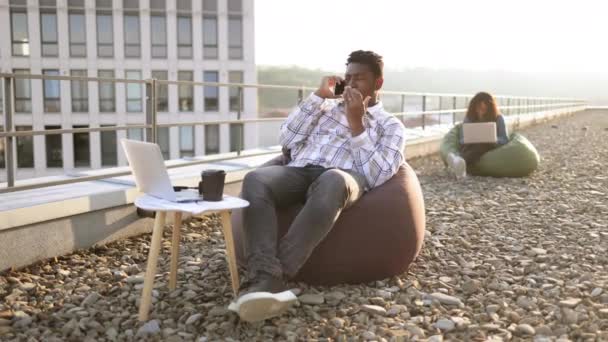 Beztroski Afroamerykanin Swobodnym Ubraniu Wykonujący Telefon Podczas Relaksu Worku Fasoli — Wideo stockowe