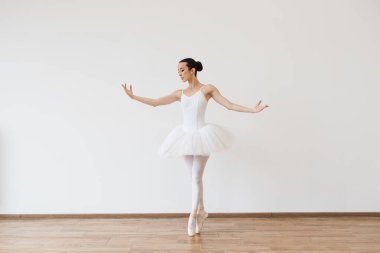 Güzel genç bayan balerin sahnede çaba harcamadan eğiliyor. Ahenk içinde vücut şekli hareketi, içeride zindelik esnekliği. Tutu hareketli kadın, denge konsepti, yaşam tarzı.