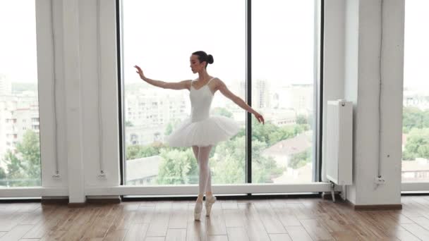 白人芭蕾舞演员在明亮的带有全景窗的班级演播室里表演 年轻优雅的芭蕾舞演员在白色宽敞的大厅里排练表演 — 图库视频影像