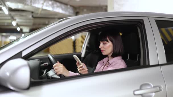 Atractiva Mujer Escribiendo Teléfono Dentro Vehículo Gris Estacionamiento Subterráneo Joven — Vídeos de Stock