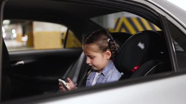 Ευτυχισμένο Μικρό Κορίτσι Κάθεται Στο Πίσω Κάθισμα Του Σύγχρονου Αυτοκινήτου — Αρχείο Βίντεο