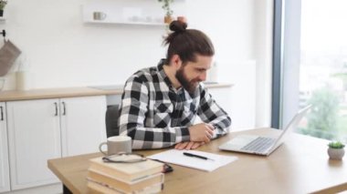 Becerikli Kafkas danışmanı teknolojileri kullanarak çevrimiçi konferans çağrısı alıyor. Ofisteki meslektaşını selamlarken taşınabilir bilgisayarın webcam 'ine bakan neşeli sakallı bir yetişkin..