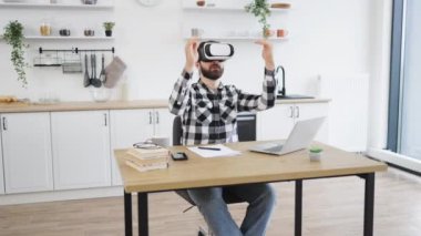 Kafkas teknoloji yöneticisi yeni modern cihazlardan memnun. Neşeli sakallı adam VR kulaklık takıyor ve mutfakta çalışırken mutluluktan el kol hareketi yapıyor..